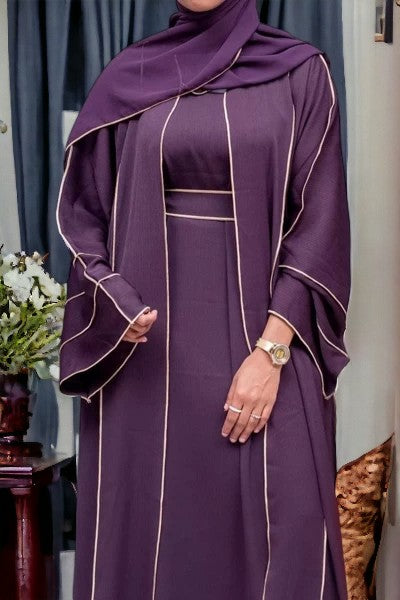 Person wearing a purple dress with white trim in an indoor setting.