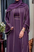 Person wearing a purple dress with white trim in an indoor setting.