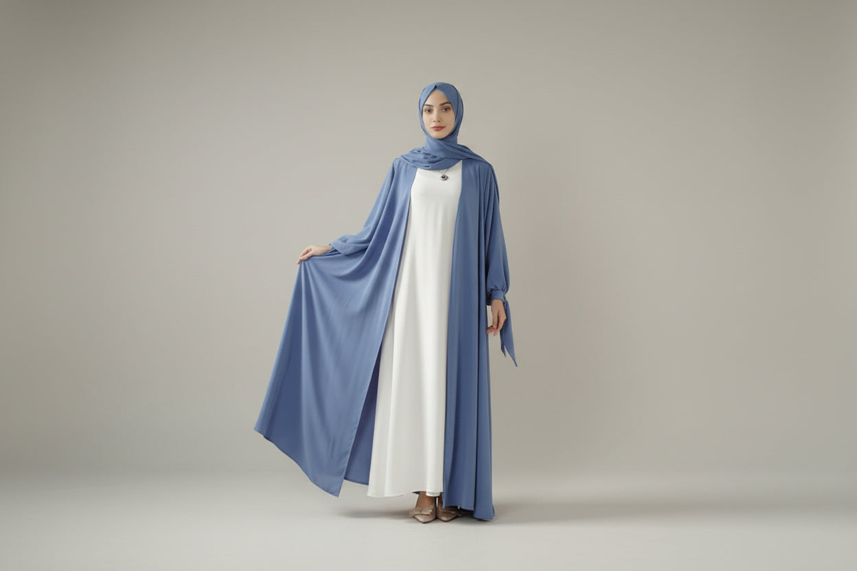 Woman wearing a blue and white abaya in a minimalistic room.