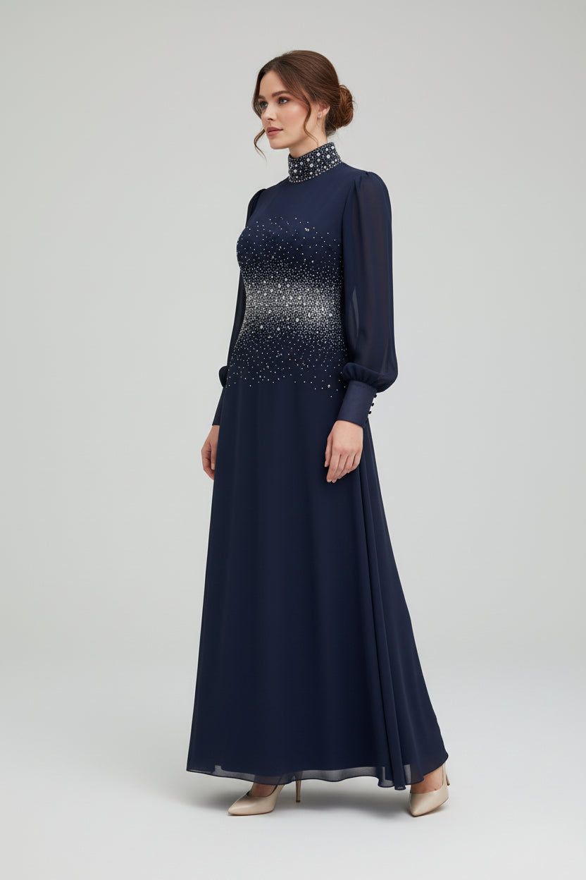 Woman wearing a long navy dress with a patterned top on a white background